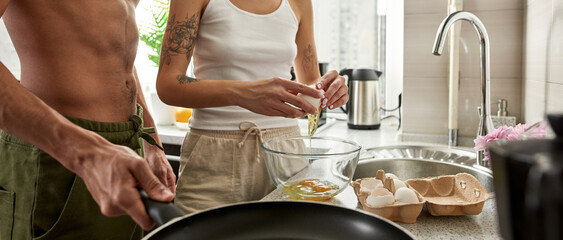 Woman break egg over bowl while man prepare pan