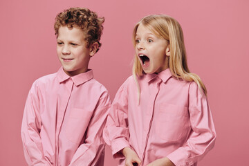 funny funny children stand in pink clothes on a pink background and the girl screams loudly looking to the side