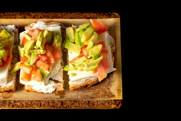 Bruschetta with avocado, tomato and goat cheese on a wooden plate. Healthy breakfast concept. High quality photo