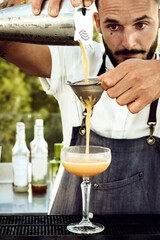 brunette guy making a drink in a daytime bar