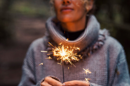 Close up of woman people holding sparkler and celebrate outdoor. New year eve and christmas celebration concept. Happiness and serene female person. Hope and future. One lady celebration. Fireworks