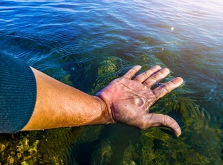 Hand of an asian man touching the water in the ocean. World water concept, clean water environment,...