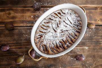 ready plum cake sprinkled with powdered sugar on a wooden table sweet dessert