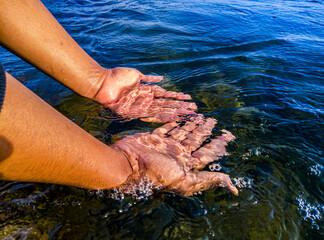 Hand of an asian man touching the water in the ocean. World water concept, clean water environment, environmental health, natural sea water cleanliness concept. World Oceans Day. Marine pollution 