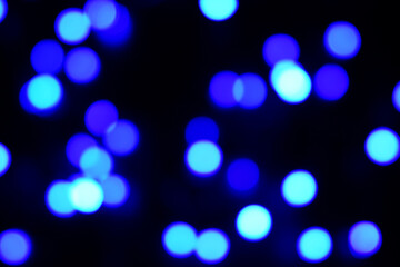 Blue circle bokeh lights blur the pitch dark background.