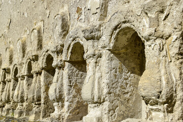 Fototapeta premium Stone relief columns carved in the wall. Texture of old dilapidated masonry. Ancient half-ruined synagogue. Rashkov, Moldova. Selective focus.