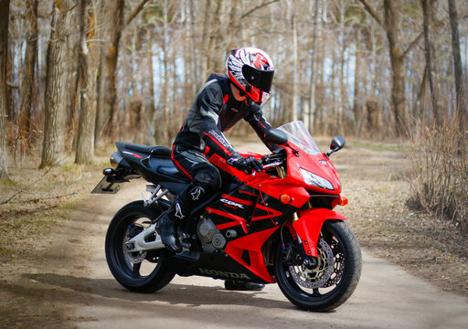 KRASNOYARSK, RUSSIA - April 21, 2018: Beautiful motorcyclist in full gear and helmet on a red and black Honda 2005 CBR 600 RR (PC37)
