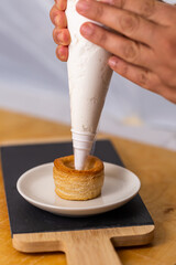 hand filling the vol au vent with cream.