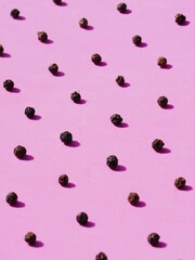 Black pepper spice grains on pink seamless pattern. Cooking spice used by Indians traditionally.