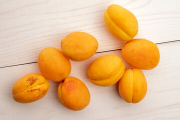 Several organic yellow pineapple apricots, close-up, on a white wooden table, top view.