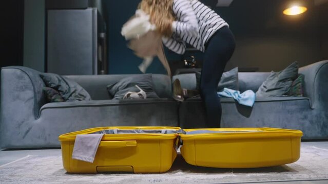 Woman packing suitcase in hurry for vacation trip, runs in a rush. Female is late on airplane, quickly packs luggage, leaves apartment for travel. Female has little time to put clothes, shoes to bag.