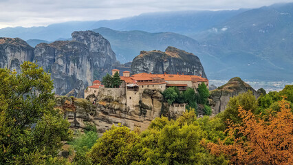 Fototapeta na wymiar Scenic view of Holy Monastery of Varlaam on cloudy foggy day, Kalambaka, Meteora, Thessaly, Greece, Europe. Rock formations overgrown with green moss creating moody atmosphere. UNESCO World Heritage