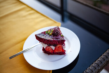 Side view of a piece of blueberry pie on a white plate with a yellow background.