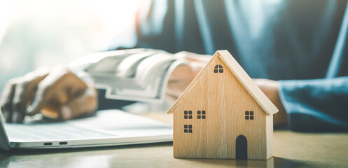 Men holding house model in hand and calculating financial chart for investment to buying property.	
