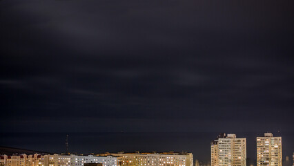 Fototapeta na wymiar Roofs of houses at night under blue cloudy sky