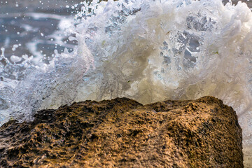Sea waves break on a sea rock with water splashes