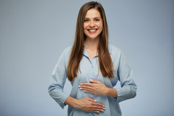 Smiling, happy woman with pleasant feeling in her belly, holding hands on her stomach. isolated portrait.