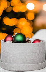 Round box with Christmas toys against the background of Christmas lights