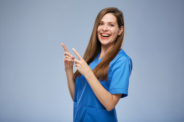 Smiling nurse woman pointing fingers up. Isolated female portrait.