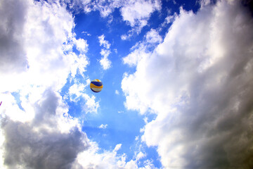 Fototapeta na wymiar Volleyball ball flies in the sky among the clouds