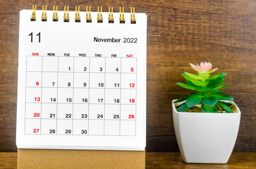 The November 2022 Monthly desk calendar for 2022 year with small plant on wooden table.