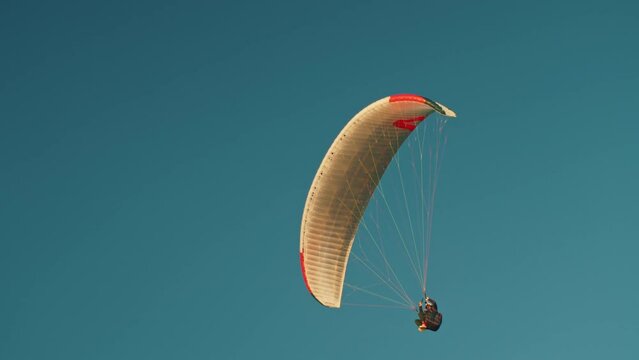 Extreme sport paraglider in the blue sky at sunset. Paraglider soaring against the backdrop of a sunny blue sky. 