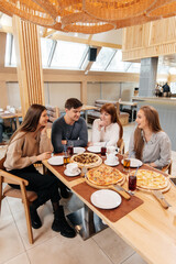 A group of friends is having pizza in a cozy restaurant. Meeting friends over dinner, socializing with a friendly company.