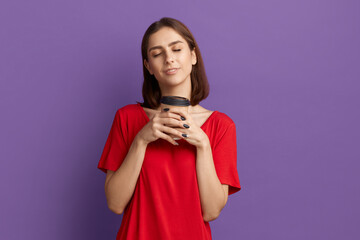 Coffee is a best drink. Satisfied young pretty brunette girl in red t-shirt holds disposable cup...