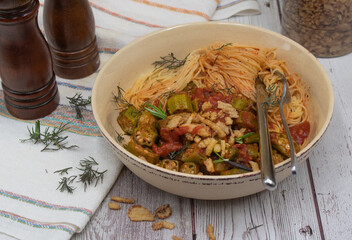 Indian vegan angel food pasta with okra and tomato sauce, wooden table