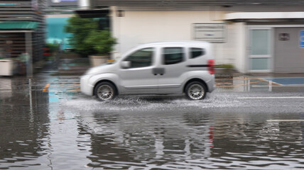 Blur car running and splashing flood water on the flooded street which caused by heavy rain and blocked drainage pipes.                             © KPD
