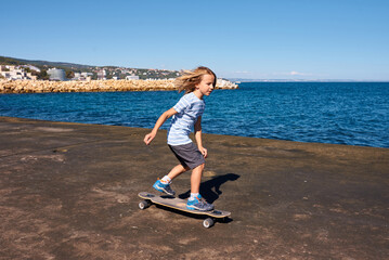 Boy riding a longboard on a pier at sunny day