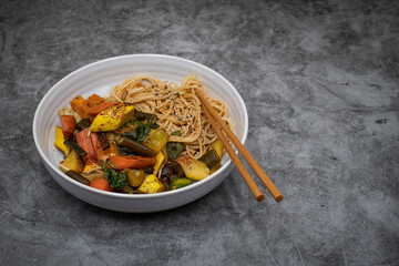 Vegan stir fry with noodles: carrot, squash and sea weed tubes