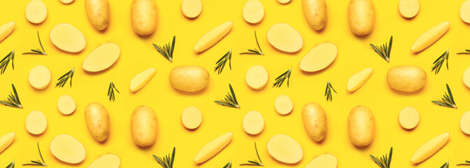 Raw potatoes with rosemary on yellow background