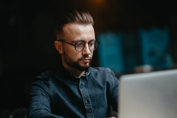 concentrated young male freelancer works on the internet in a cozy office.