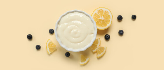 Bowl of tasty pudding with blueberries and lemon slices on beige background, top view