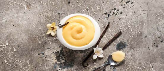 Bowl of tasty vanilla pudding on grunge background, top view