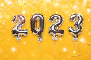 Figure 2023 made of silver balloons on yellow background