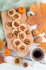 Obraz na płótnie Canvas On the table is a wooden board with cookies and nuts and a cup of coffee and autumn maple leaves.