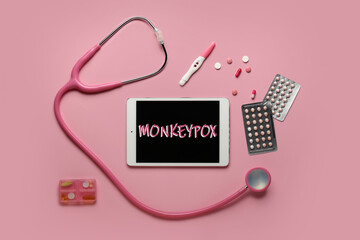 Tablet computer with word MONKEYPOX on screen, drugs and stethoscope on pink background