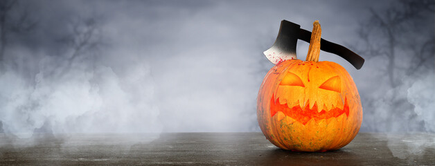 Creepy Halloween pumpkin with axe on table at night