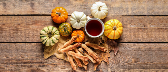Halloween cookies, autumn leaves, pumpkins and tea on wooden background, top view