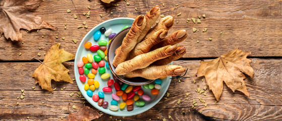 Halloween cookies, autumn leaves and candies on wooden background