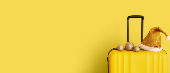 Suitcase, Santa hat and decor on yellow background with space for text. Christmas vacation concept