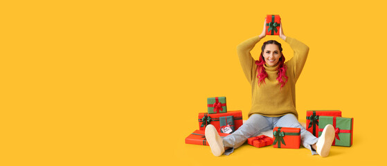 Obraz na płótnie Canvas Beautiful woman and many Christmas gifts on yellow background with space for text