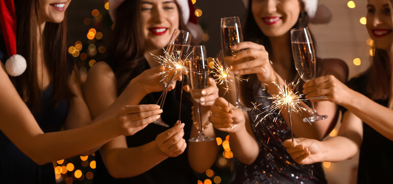 Happy women with Christmas sparklers and glasses of champagne at party