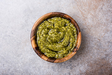 Fototapeta na wymiar Bright green pesto sause in wooden bowl