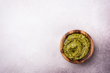 Obraz na płótnie Canvas Bright green pesto sause in wooden bowl