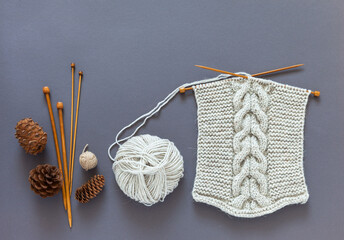 Knitting as hobby and pleasure. Knit warm scarf with braid pattern from natural wool yarn. Wooden...