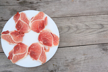 Raw Pork Slice in White Round Plate on old Wooden Table. Slide raw meat on the table. Top view