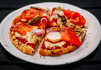mini pita pizza with Mozzarella cheese, ham, chicken, mushrooms, salami. Italian pizza on wooden table background outdoor